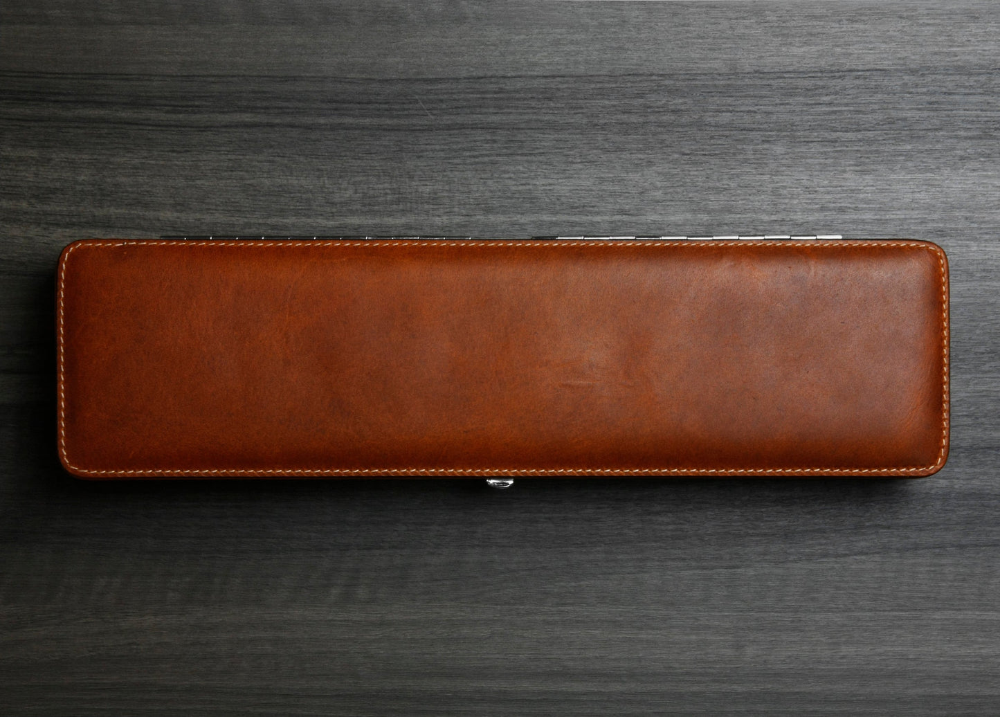 Top-down photograph of the closed F. Hammann 3976 Ruler Box in rich Coxorange leather on a dark wood grain surface.