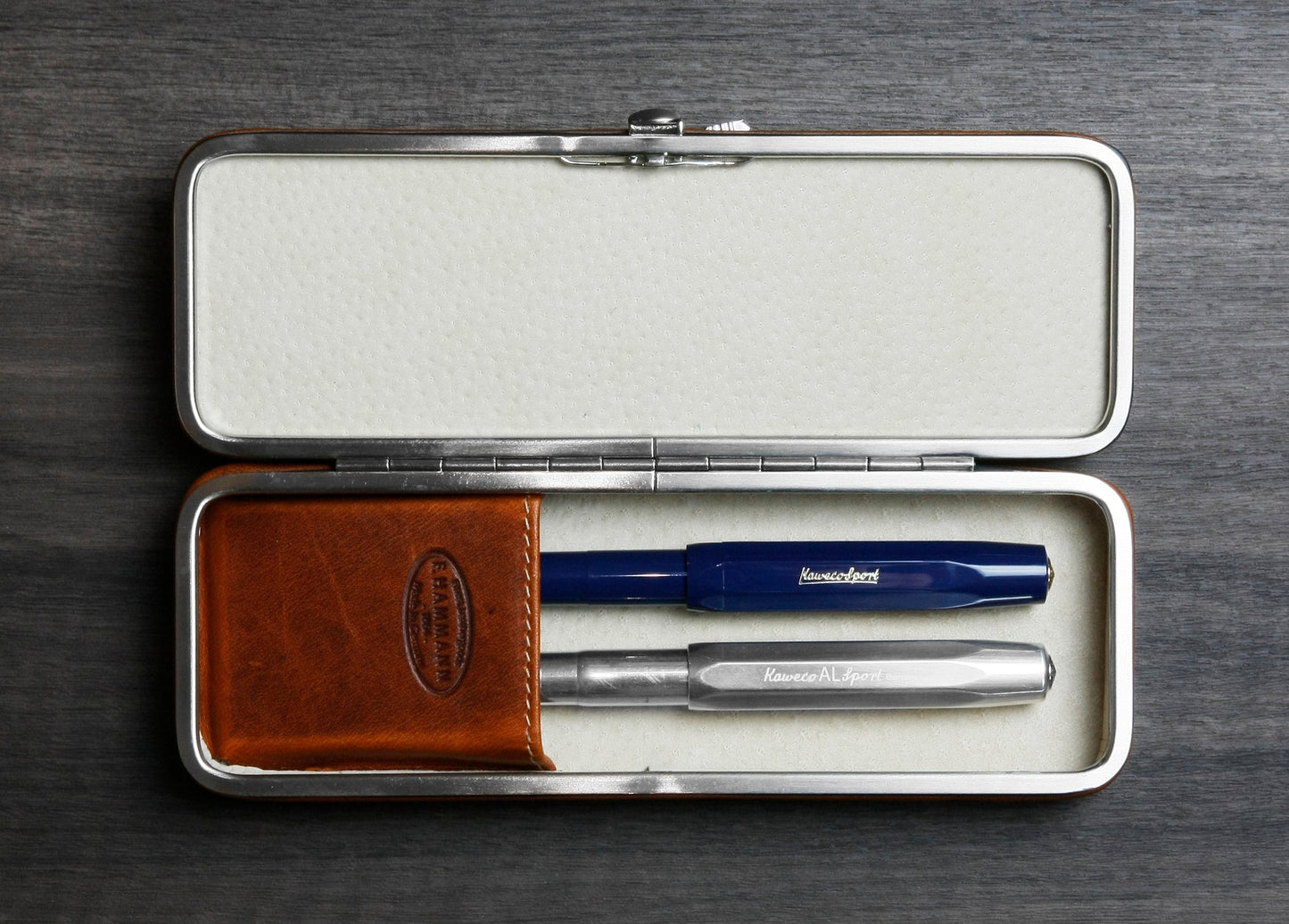 Open F. Hammann 3983 framed leather case in Coxorange holding two Kaweco fountain pens securely within its hidden flexible loop system.